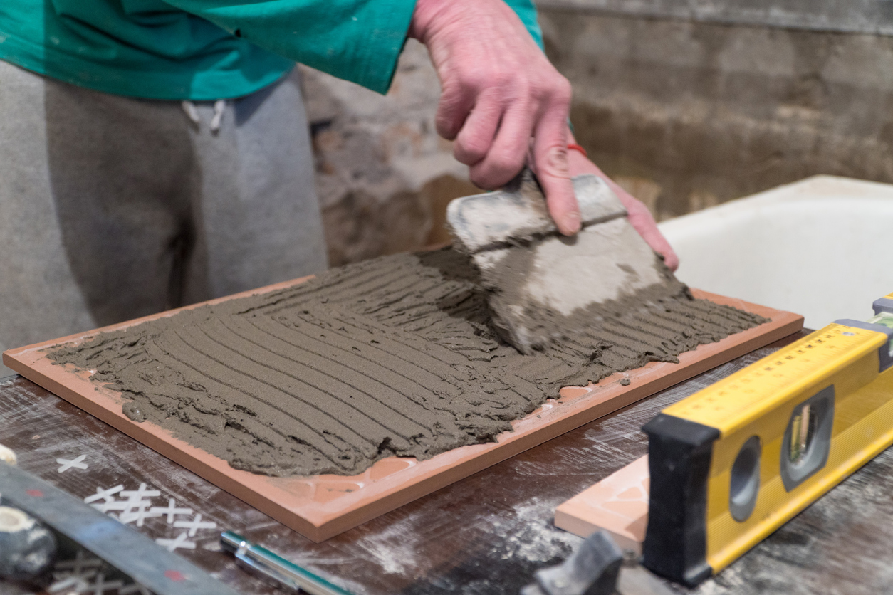 Worker applies cement adhesive on the tiles. Finishing works, blurred focus. The technology of laying tile.