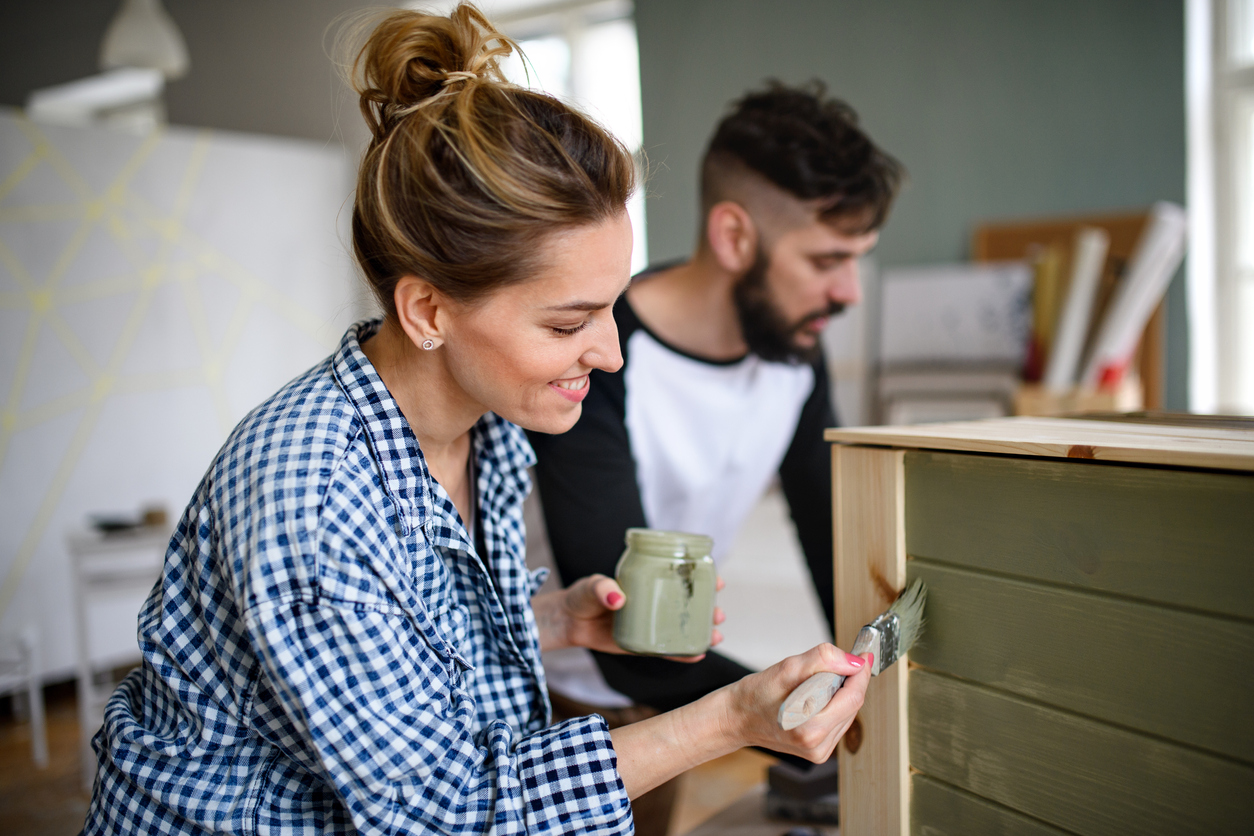 woman painting the back of a dresser green