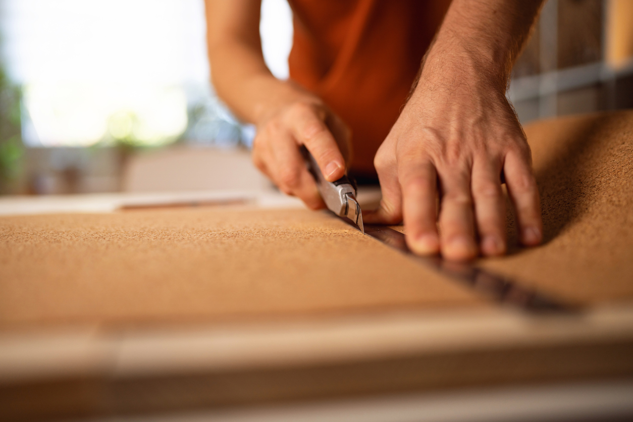 Unrecognizable male architect cutting the cork with scalpel while making architectural model