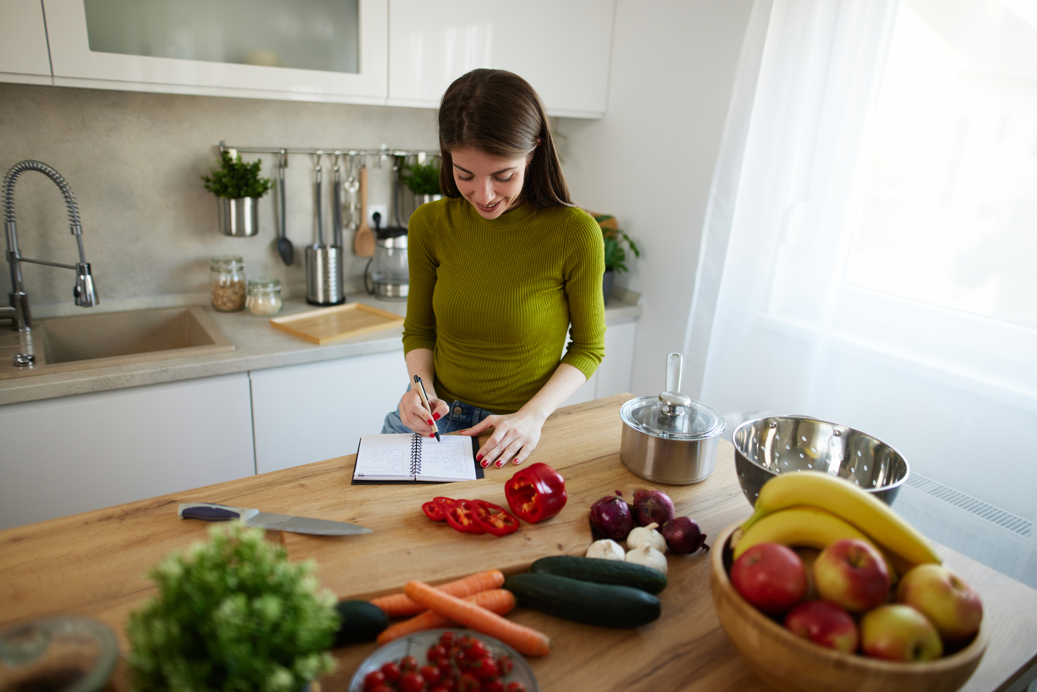 Young woman reading cookbook in the kitchen, looking for recipe