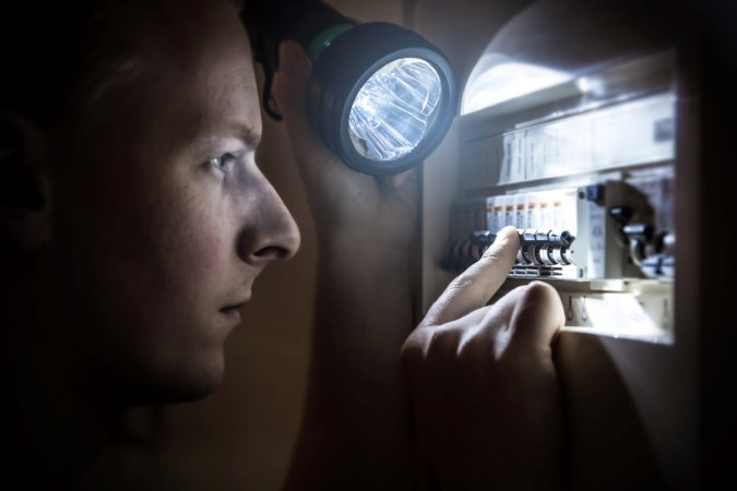 Person checking breakers with flashlight