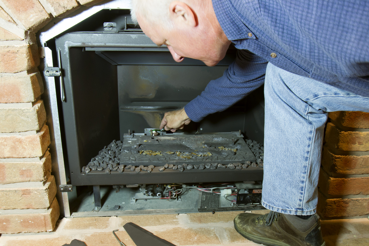 Man doing installation, repair, or seasonal maintenance on a built-in gas fireplace