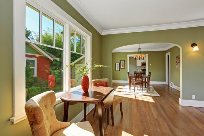 House interior with open floor plan. Sitting area by the window with table and chairs and dining room with archway