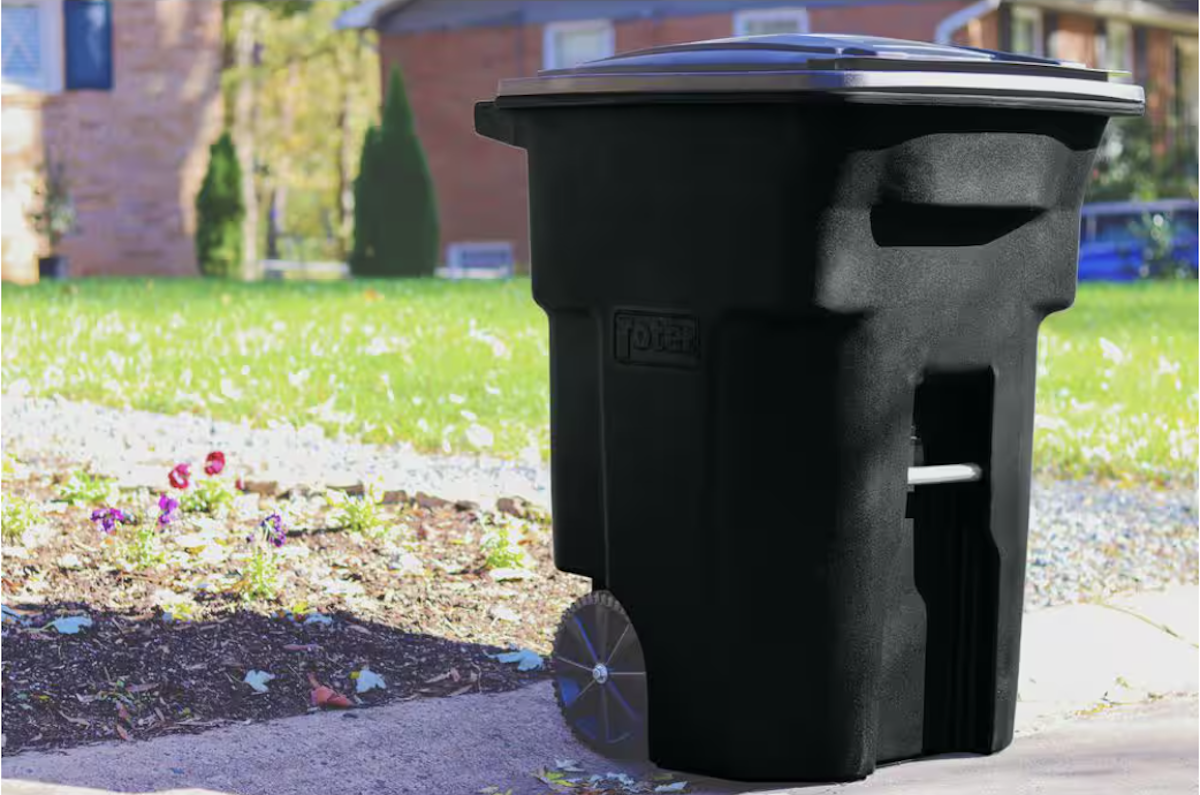 A large 64- to 96-Gallon trash can sits on a curb. 