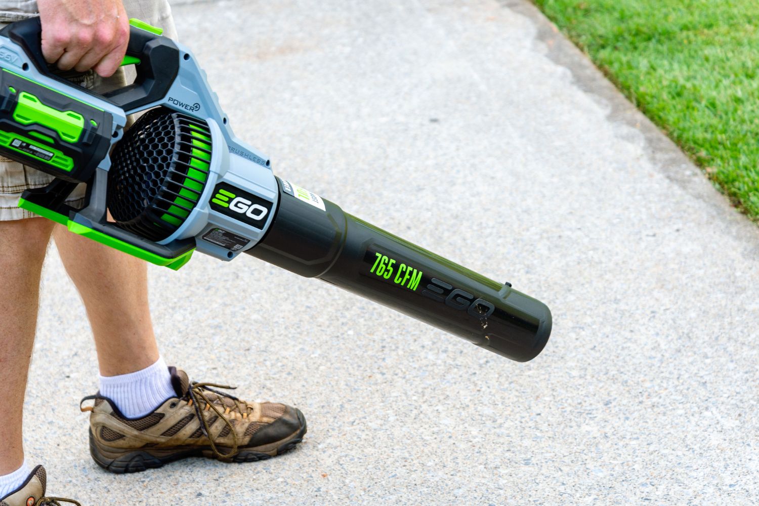 A person using the Ego Power+ 765 CFM 56V Leaf Blower to clear debris from a sidewalk.