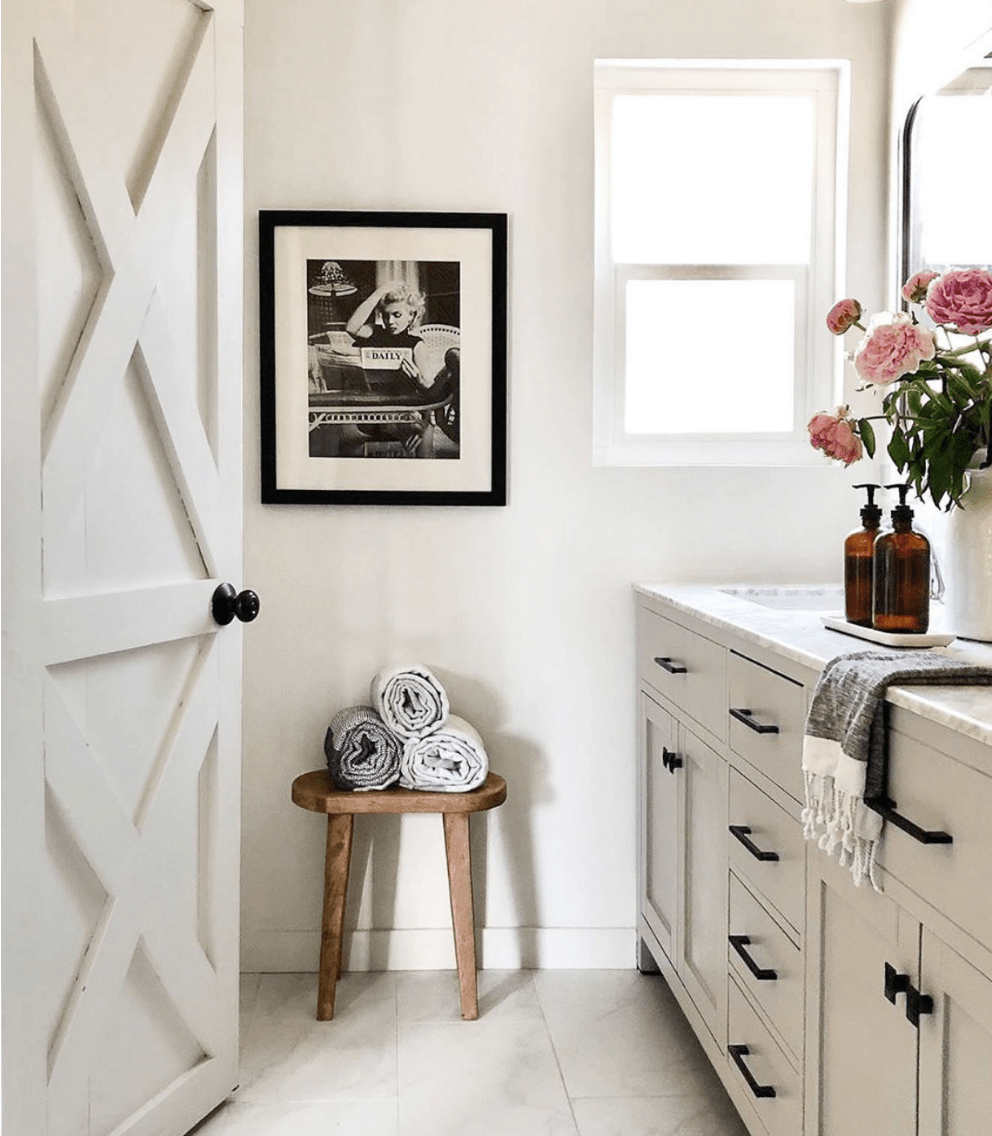 A view of a light interior bathroom with sink visible and open door and light grey walls