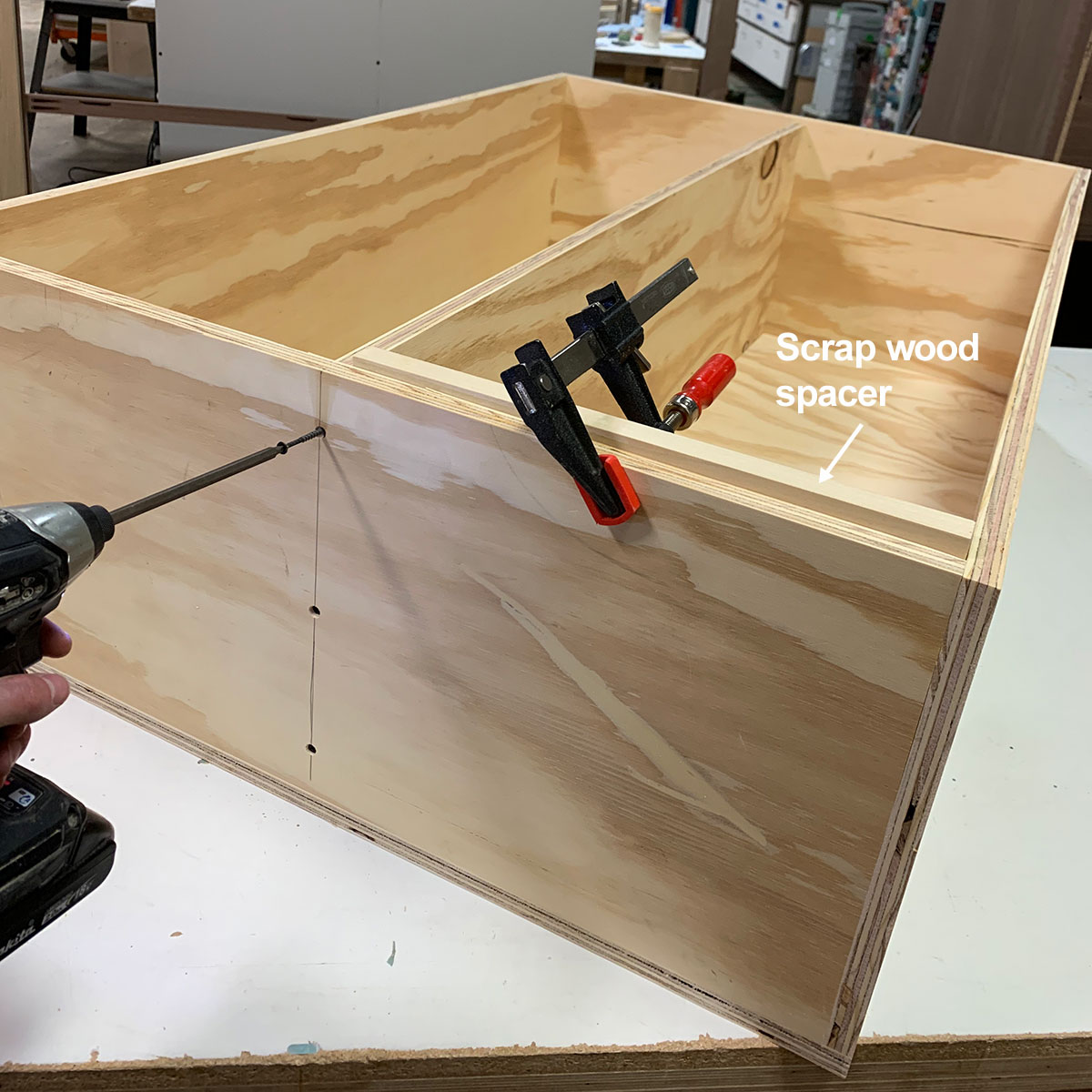 A woodworker building a cabinet with shelf in a workshop.