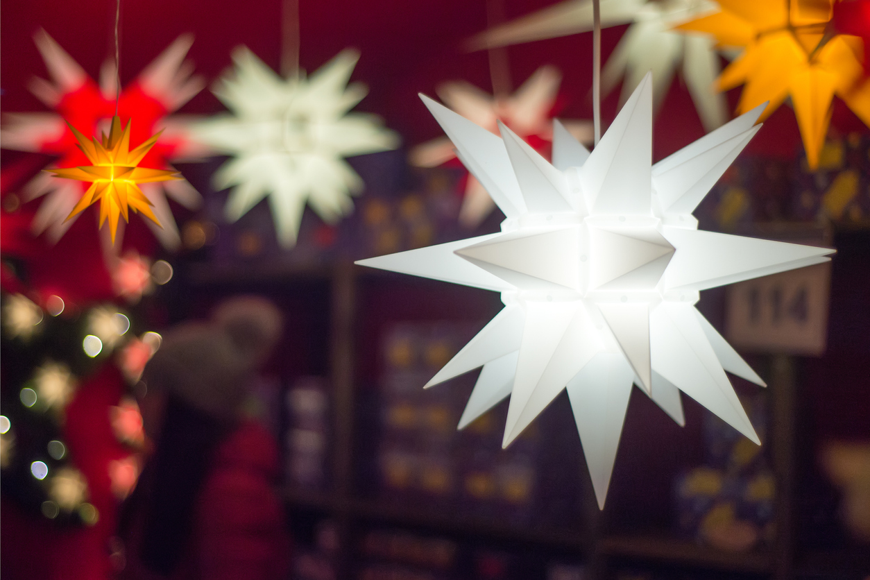 Close view of bright lit up epiphany starts hanging in front of other Christmas decorations.