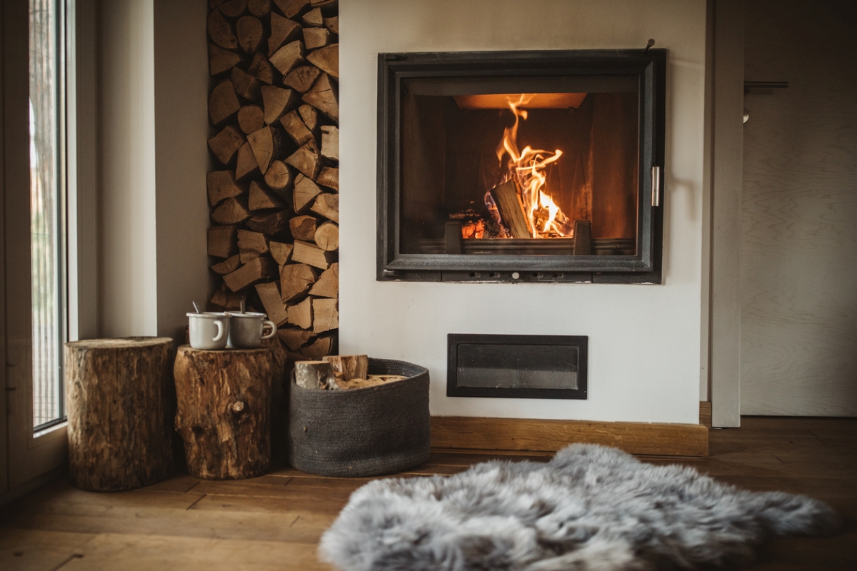 Cozy fire next to stacks of wood.