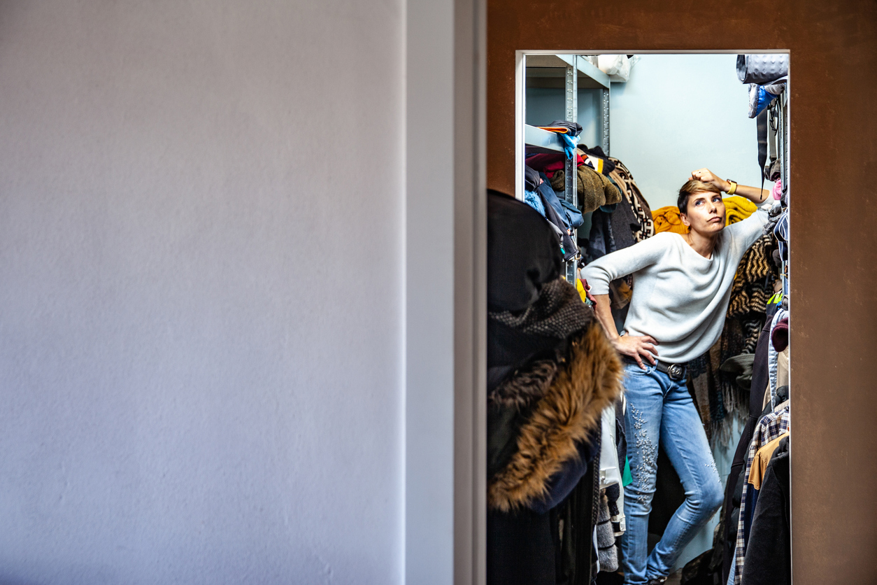 A-person-looks-exasperated-with-the-overflowing-small-closet-theyre-standing-in