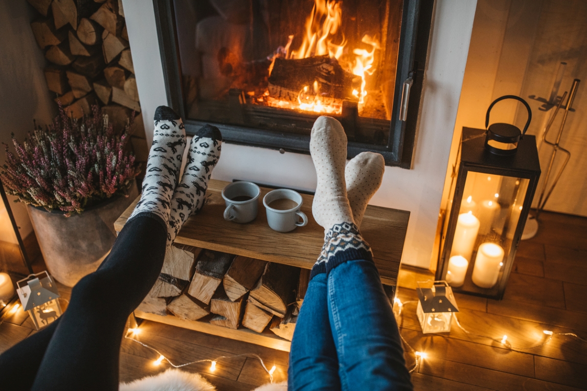 Two people with their feet towards fireplace.