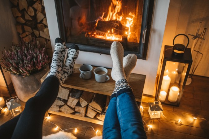 Two people with their feet towards fireplace.