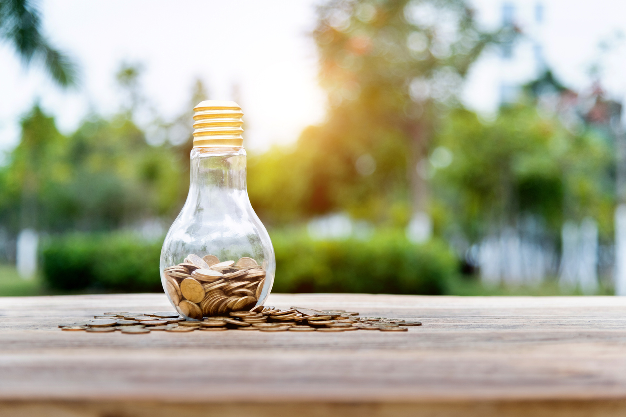 Light bulb with many coins on the table.