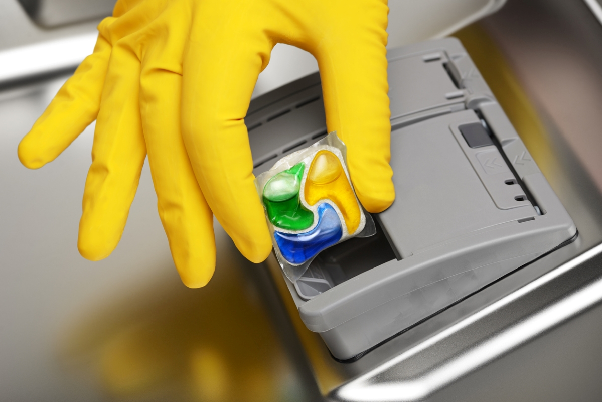 Person putting dishwasher pod in dishwasher dispenser