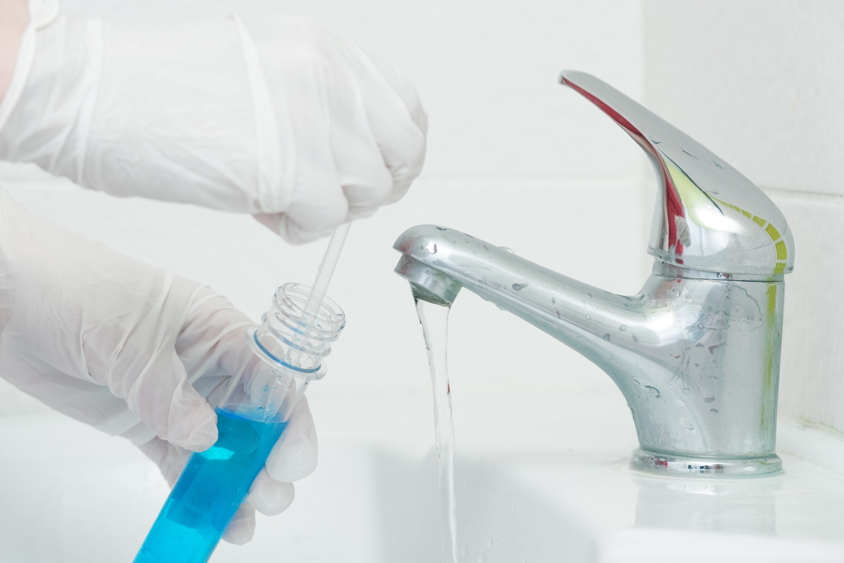 Gloved hands testing sink water