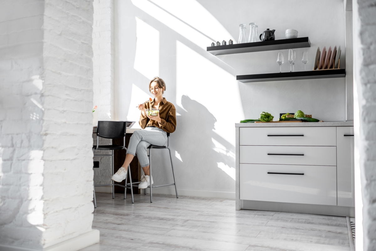 Woman eating in small kitchen.