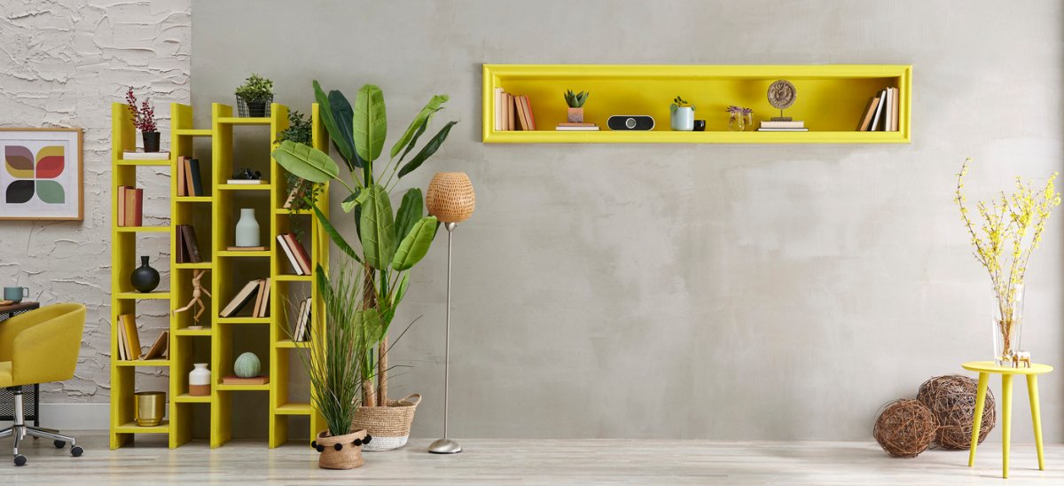 Grey stone wall, room, interior style with yellow niche, green vase of plant, bookshelf decor.