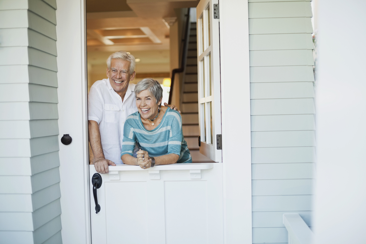 senior couple standing behind dutch door with top open