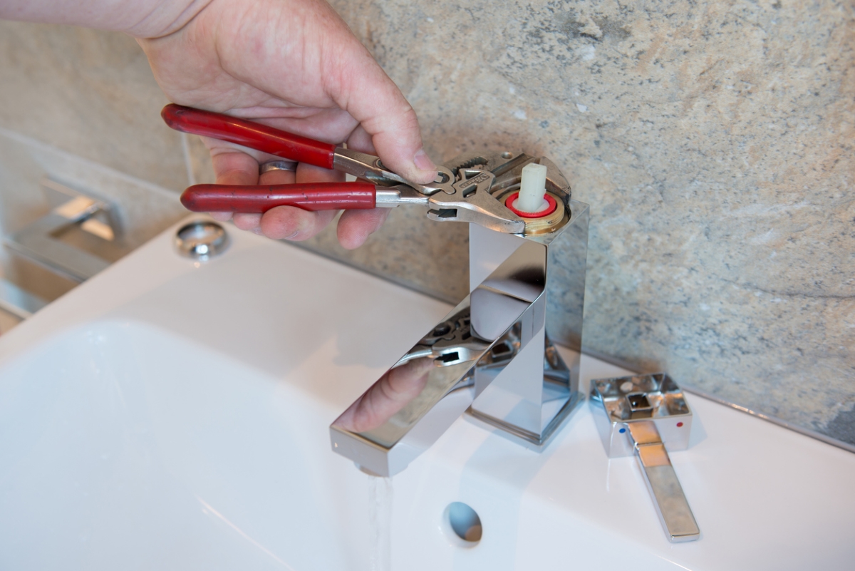 Person using tool to fix leaky faucet