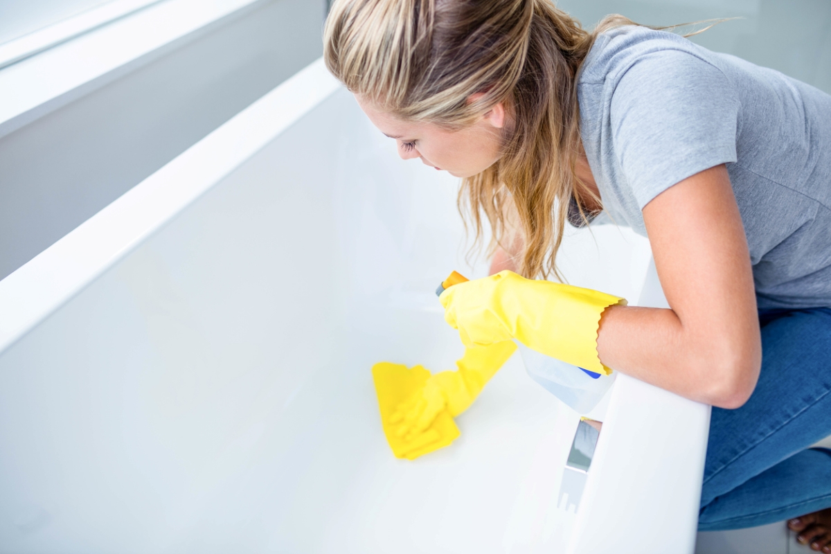 Woman cleaning tub.