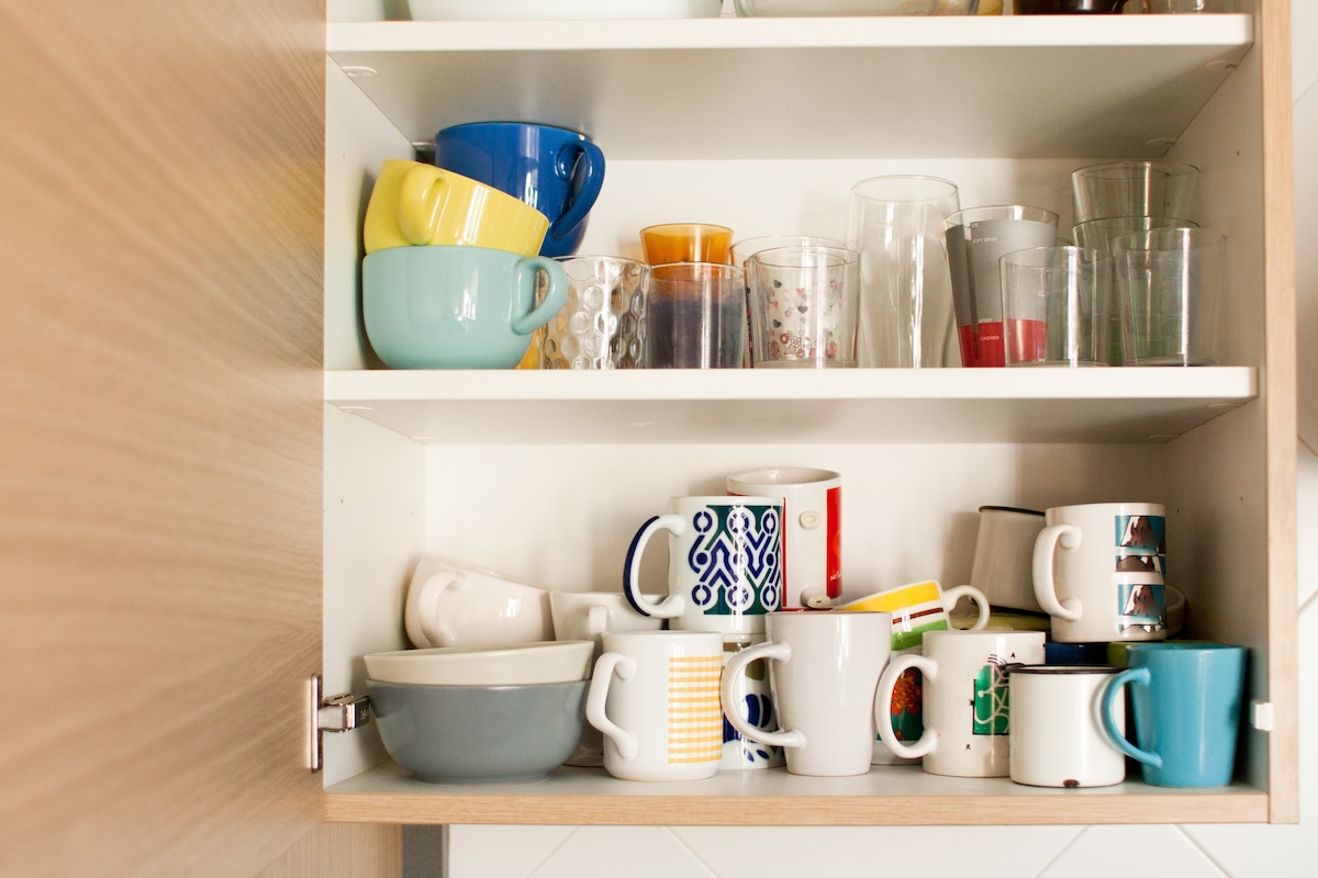 A cabinet with cluttered coffee mugs.