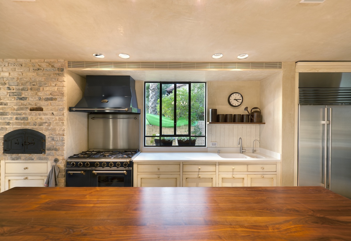 A butcher block countertop in a luxury kitchen rests with drying varnish.