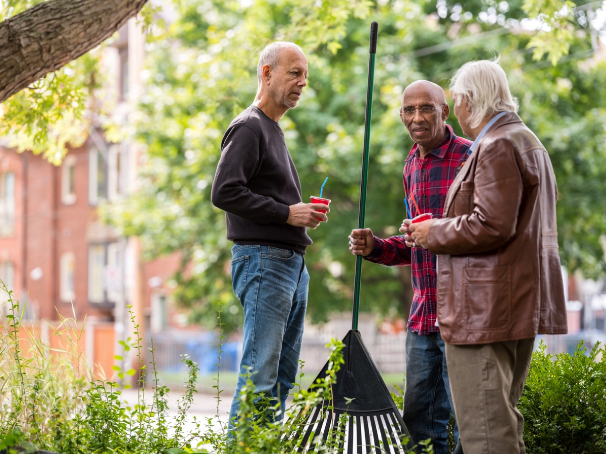 Neighbors chatting while holding rake.