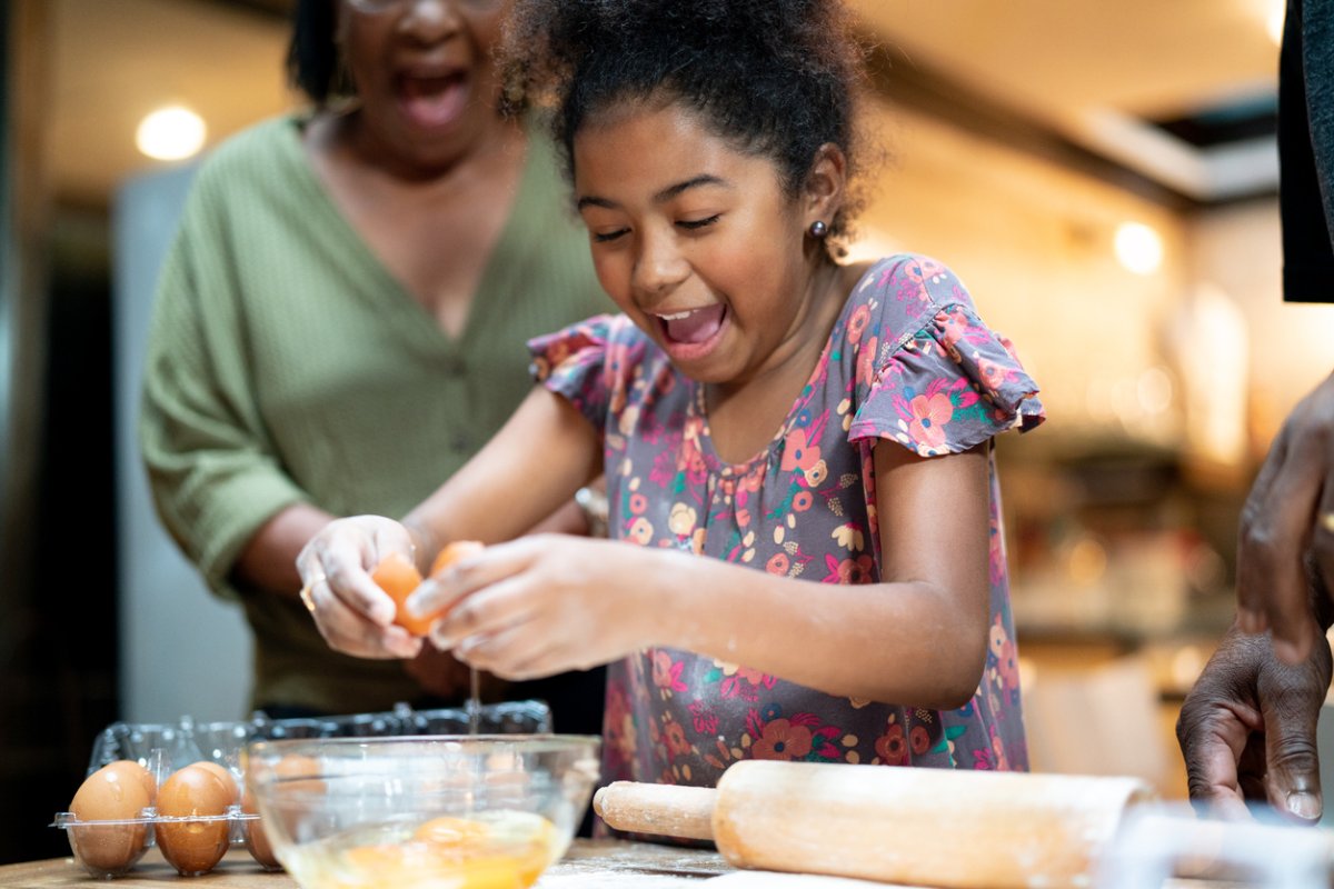 Afro hispanic-latino grandparents teaching her granddaughter how to cook