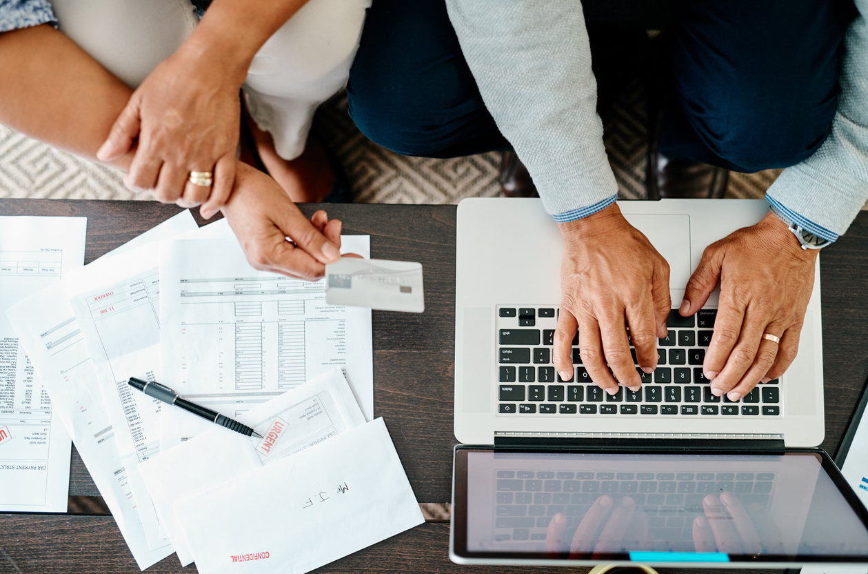 High angle shot of a couple using a laptop and credit card while sorting their finances together at home