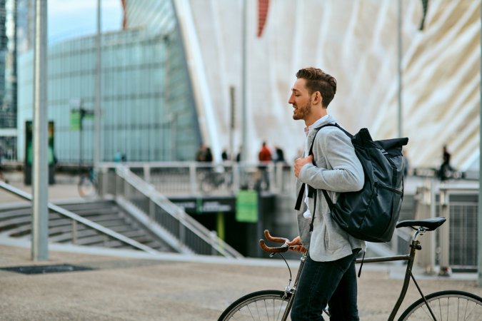 Shot of a young businessman traveling through the city with his bicycle