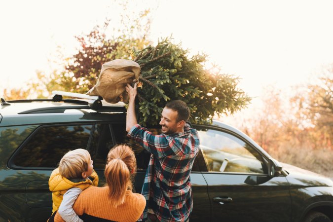 Photo of young family carrying home their Christmas tree