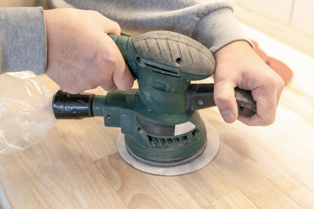 Using a wood sander on a wooden butcher block. 