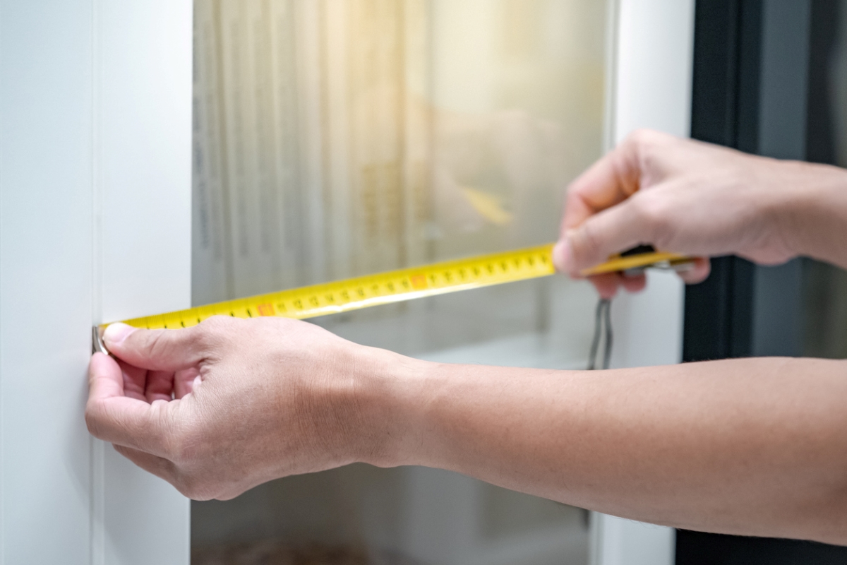 Person measuring cabinet door.