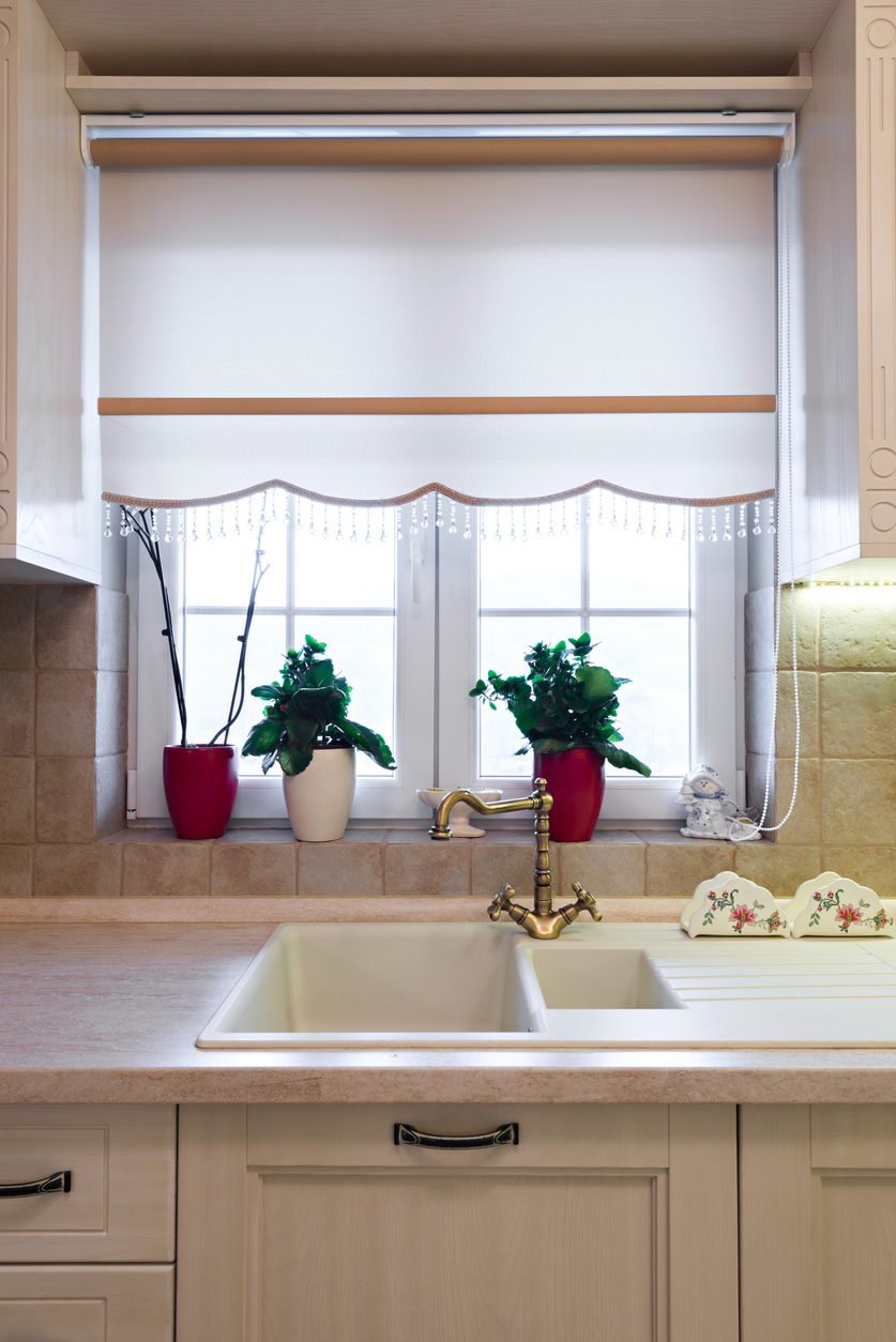 An embellished roman shade covering a small kitchen window.