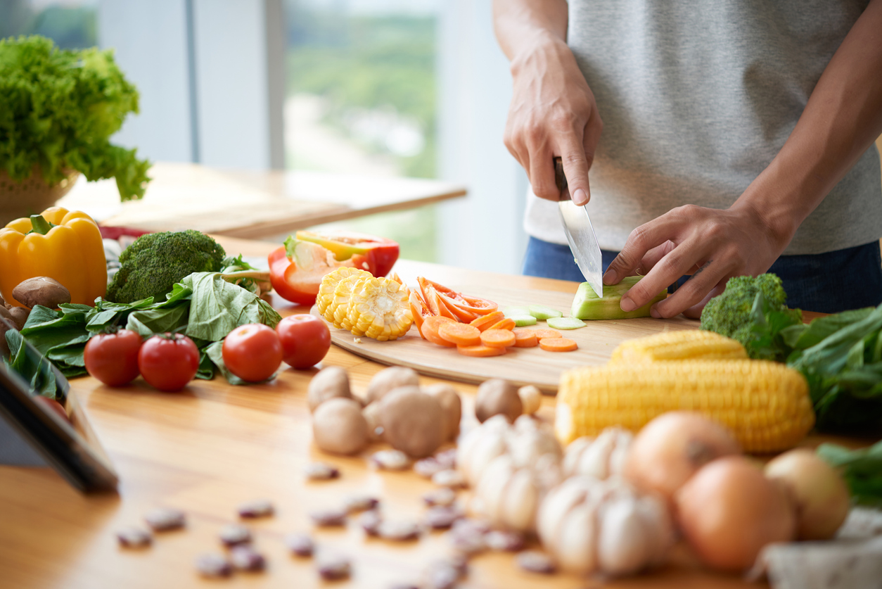 A man slices vegetables on a kitchen counter.