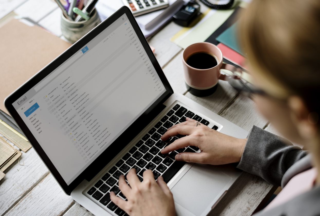 A woman going through her emails on a laptop in a home office.