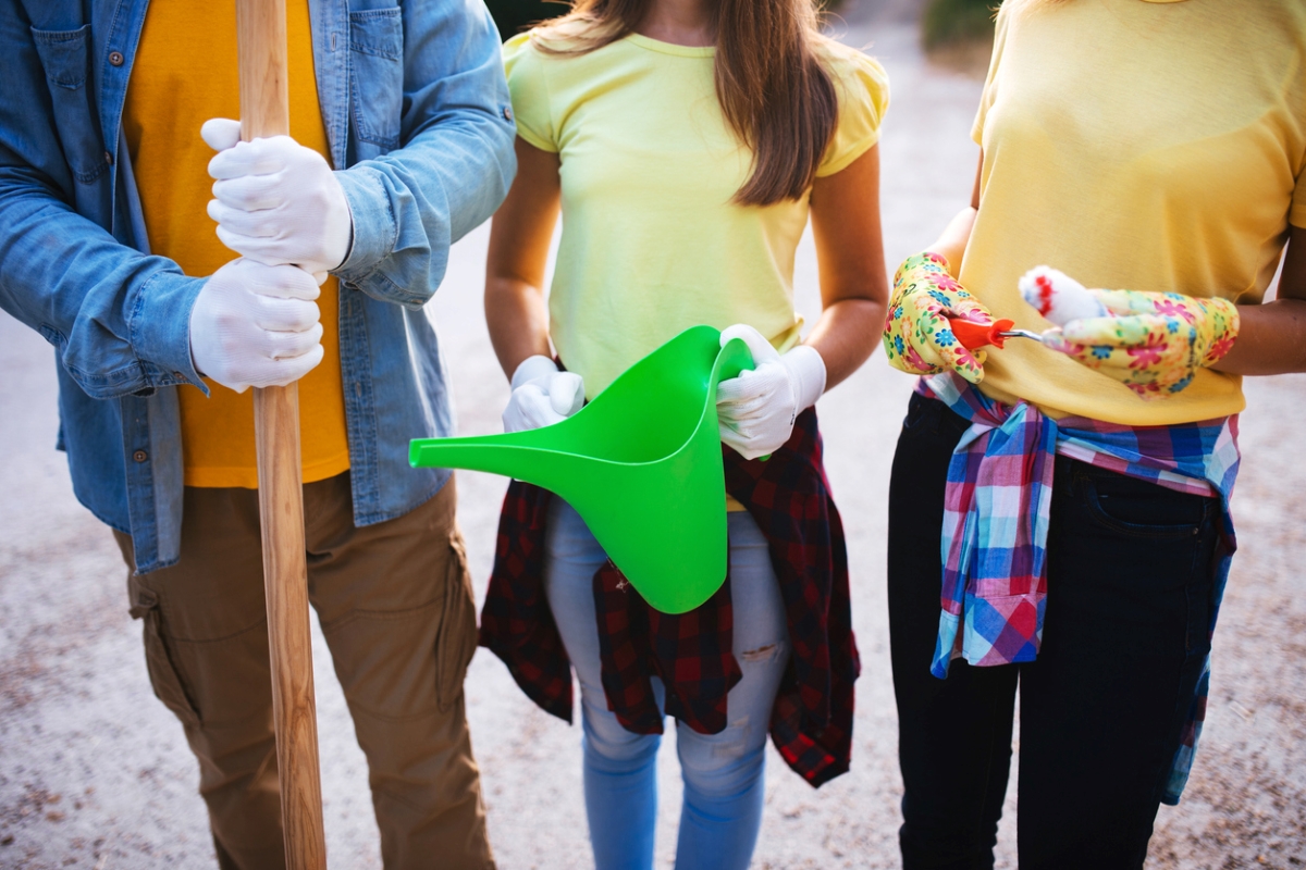 Three people holding garden tools.