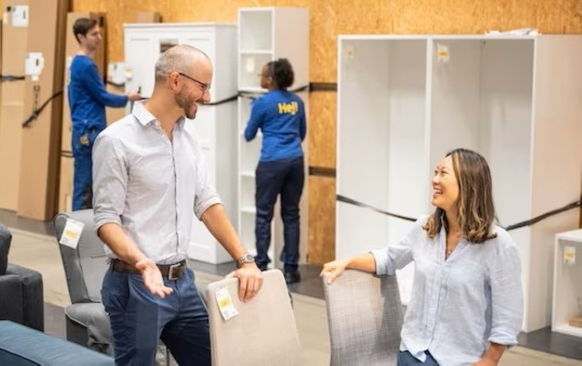 Couple talking over chairs sale.