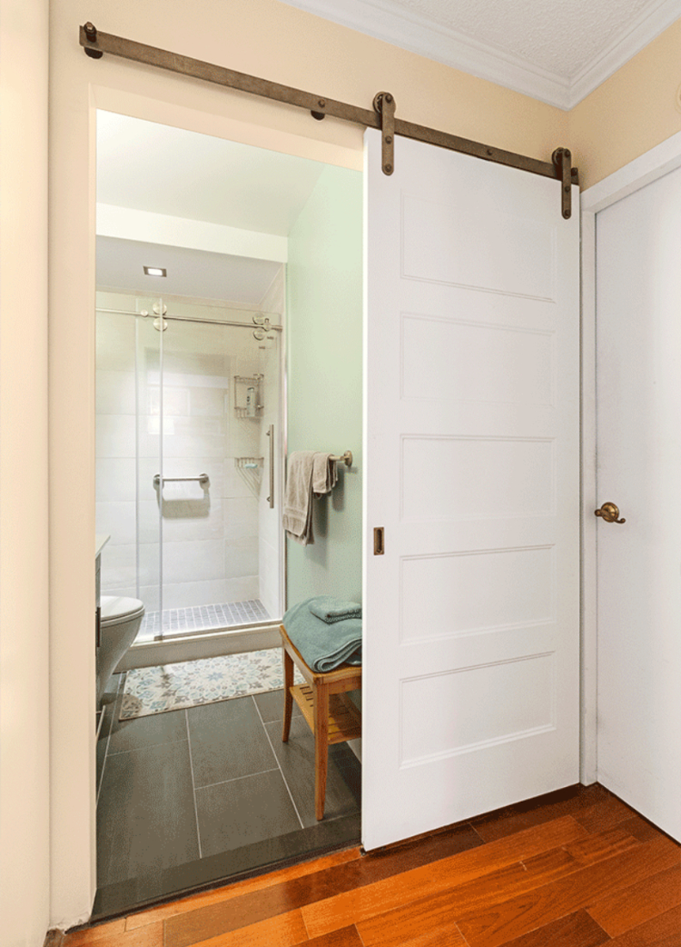 An open barn door that leads into a small en suite bathroom.