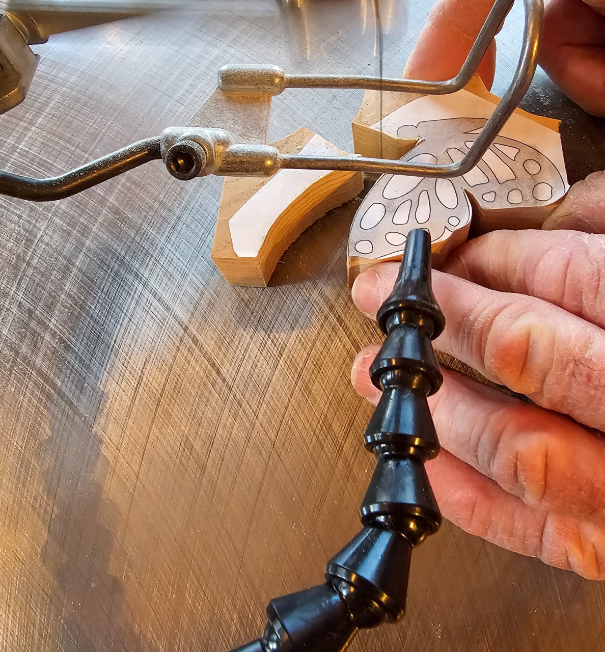 The DeWalt scroll saw in use cutting along the curved wing of a wooden butterfly while the saw's dust blower clears away sawdust.