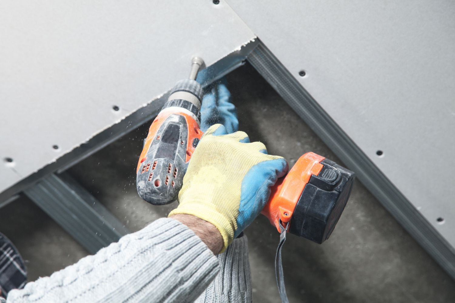 Worker Drilling into Drywall: Part of the Drop Ceiling Cost