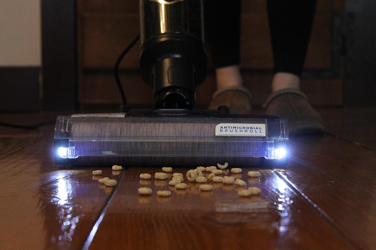 A person using the Shark HydroVac with LED lights to vacuum up spilled cereal.