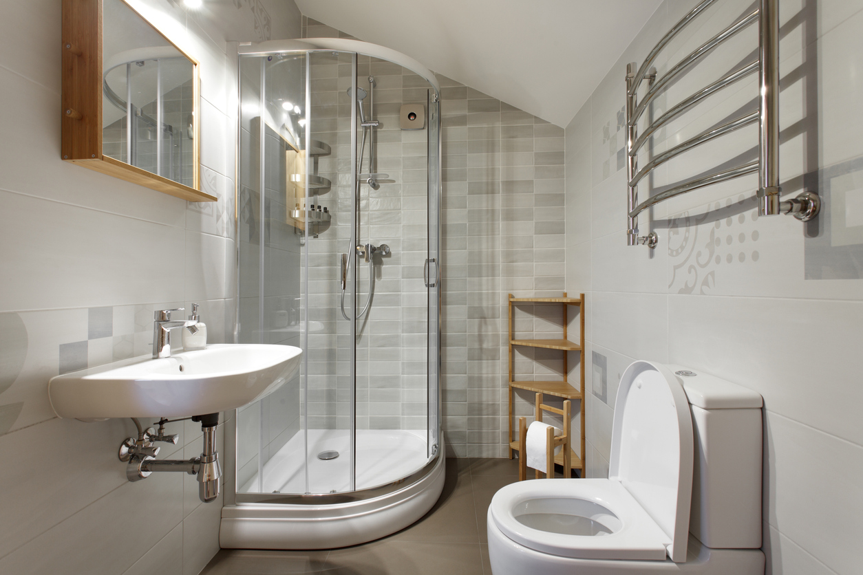 A small white bathroom with wood and stainless steel accent pieces.