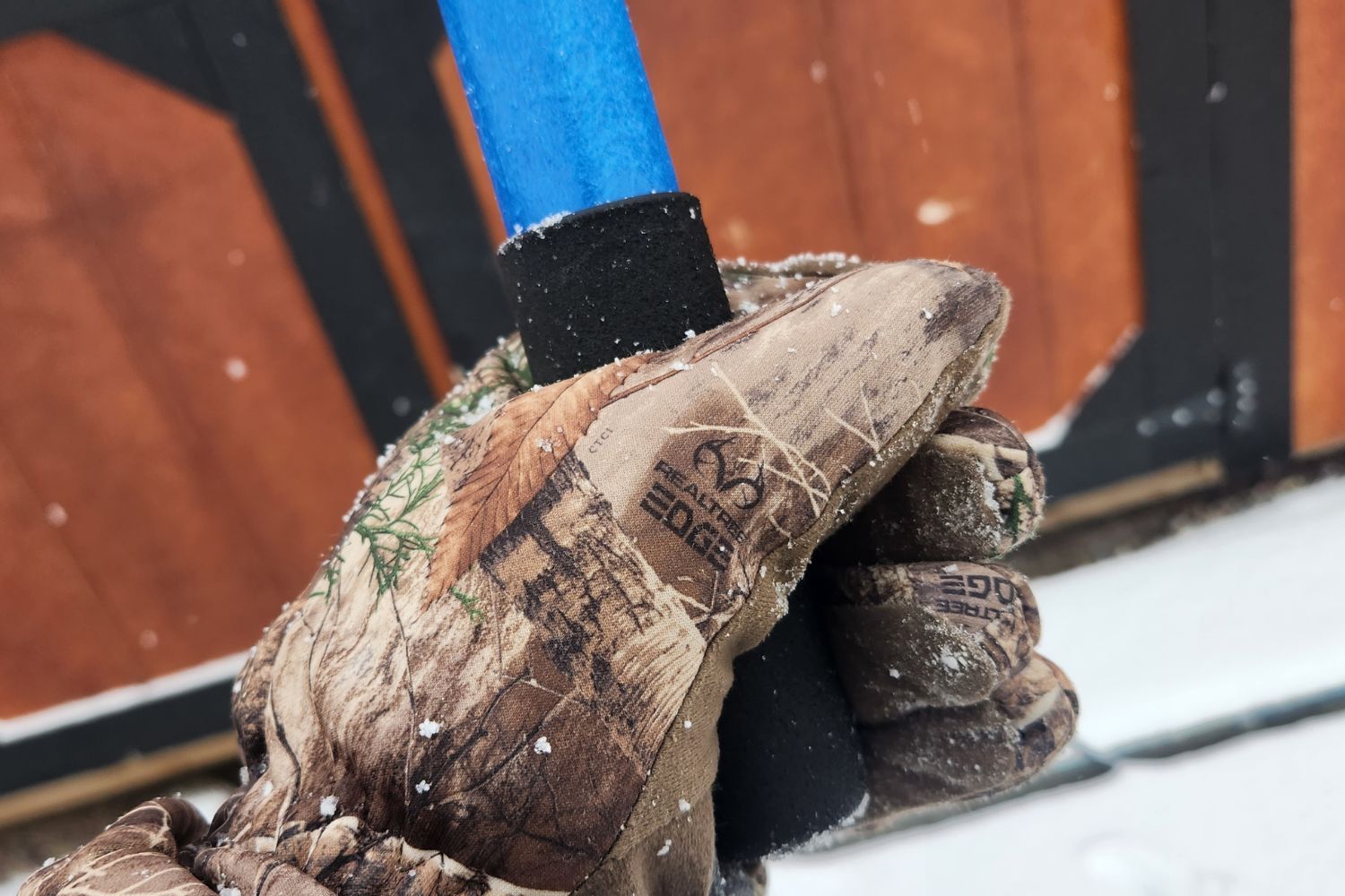 A gloved hand holding the gripped handle end of the Avalanche! roof rake.