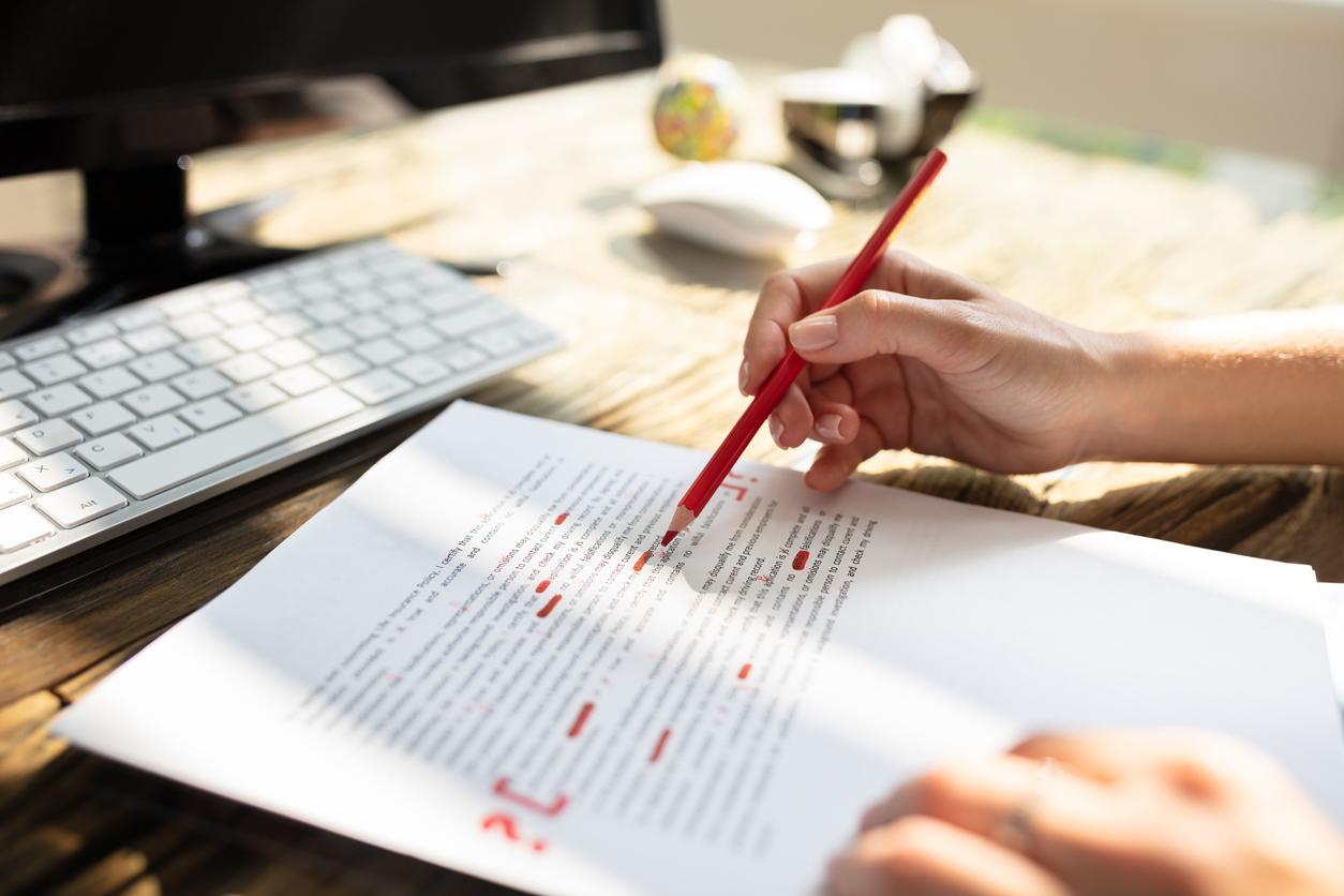 Close-up Of A Person's Hand Marking Error With Red Marker On Document