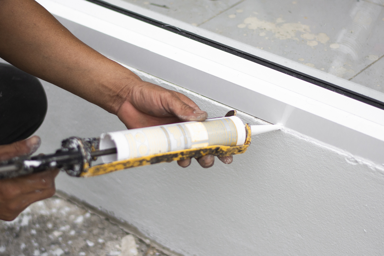 Repairman hand installing the windows with gun silicone. closeup