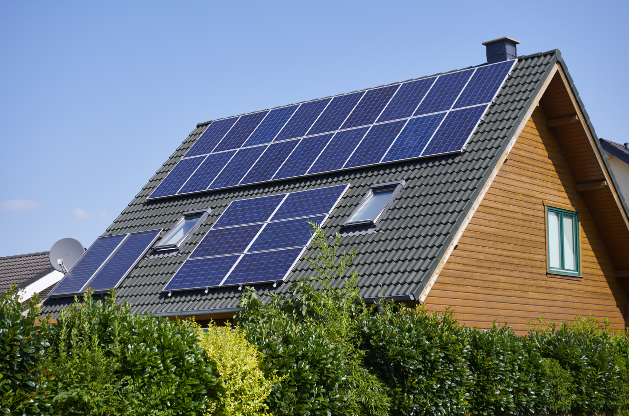 A-wood-house-has-solar-panels-along-the-black-tiled-roof.