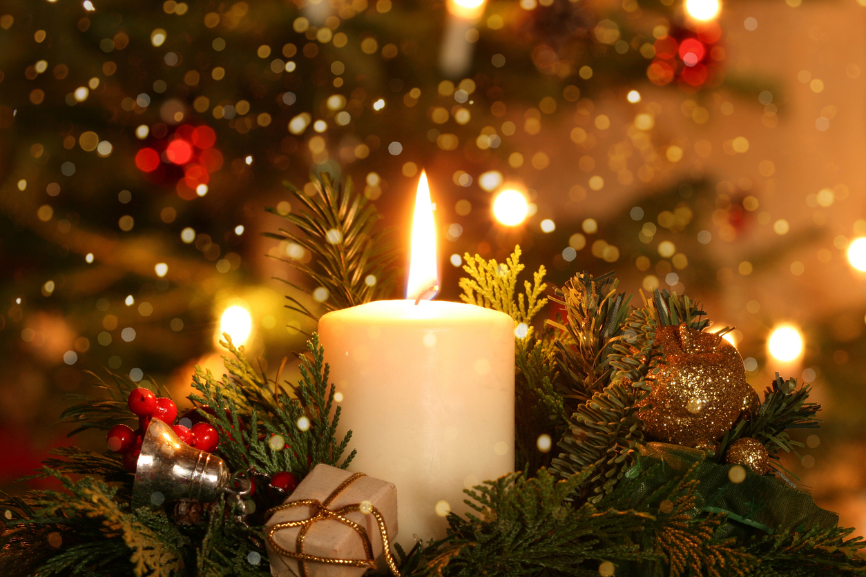 burning candle Christmas decoration with flare lights in front of a Christmas tree