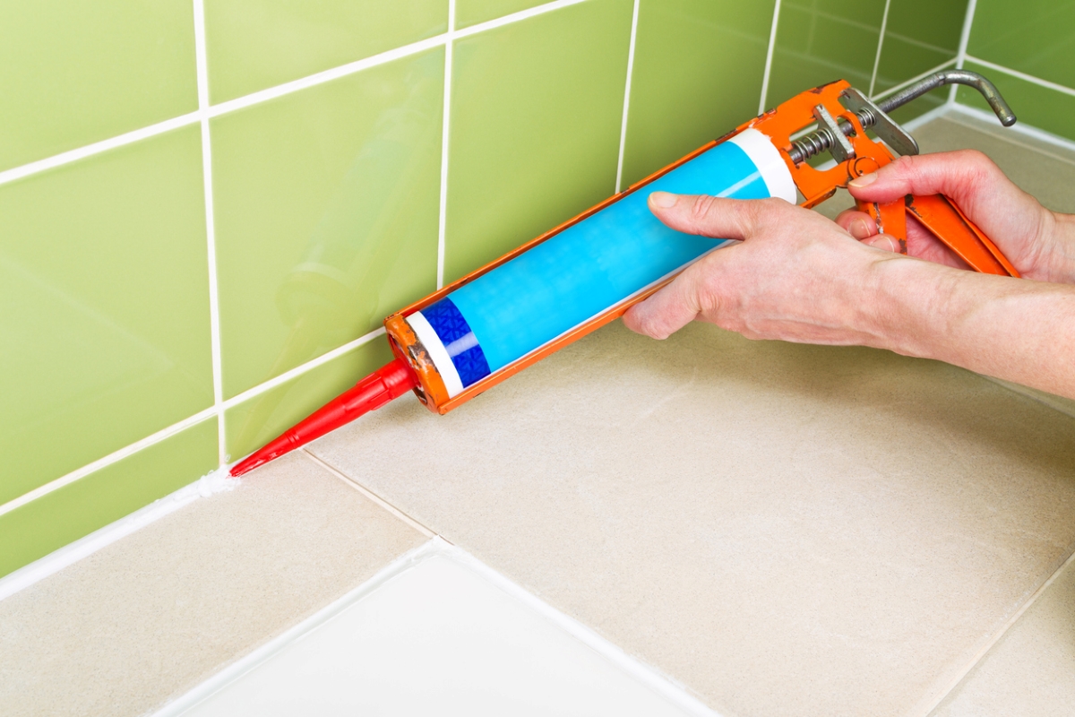 Person using caulk gun on tile.