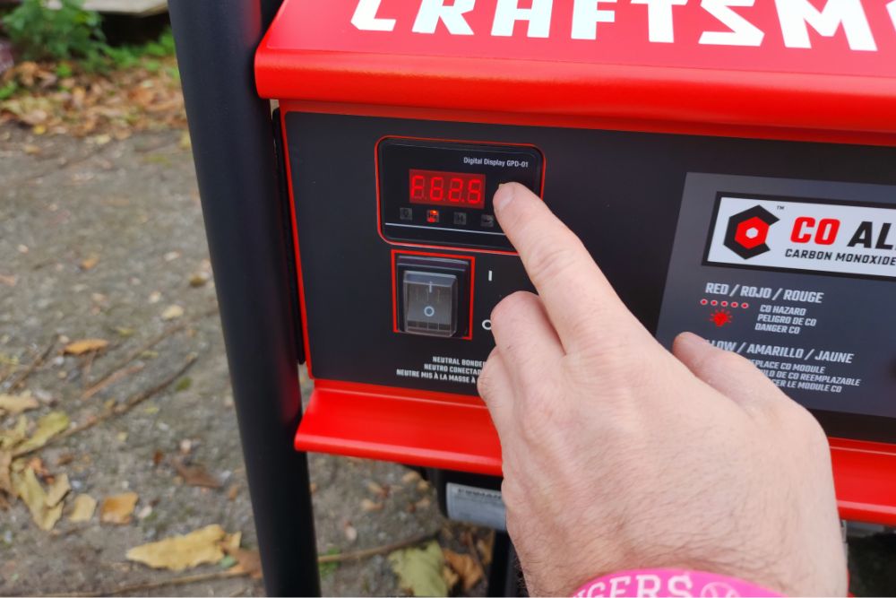 A person pressing the push-button start on the Craftsman 6000-watt generator during testing.